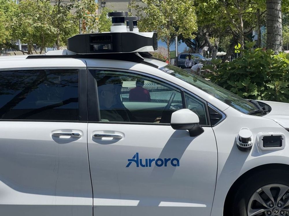  Autonomous vehicle from Aurora Innovation driving along University Avenue, with storefronts and tree-lined street in the background, Palo Alto, California, July 11, 2024.