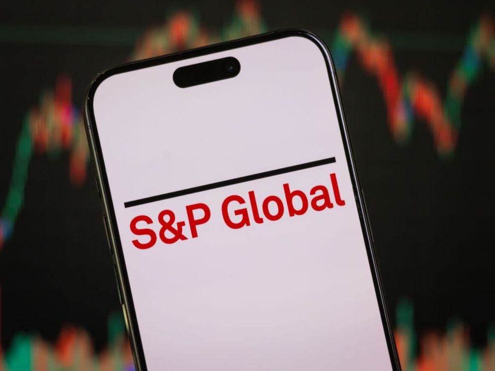 In this photo illustration, the S&P Global logo is displayed on a smartphone screen in front of a stock chart. (Photo illustration by Cheng Xin/Getty Images)