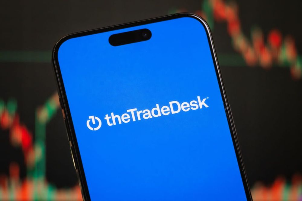 In this photo illustration, the Trade Desk logo is displayed on a smartphone screen in front of a stock chart.