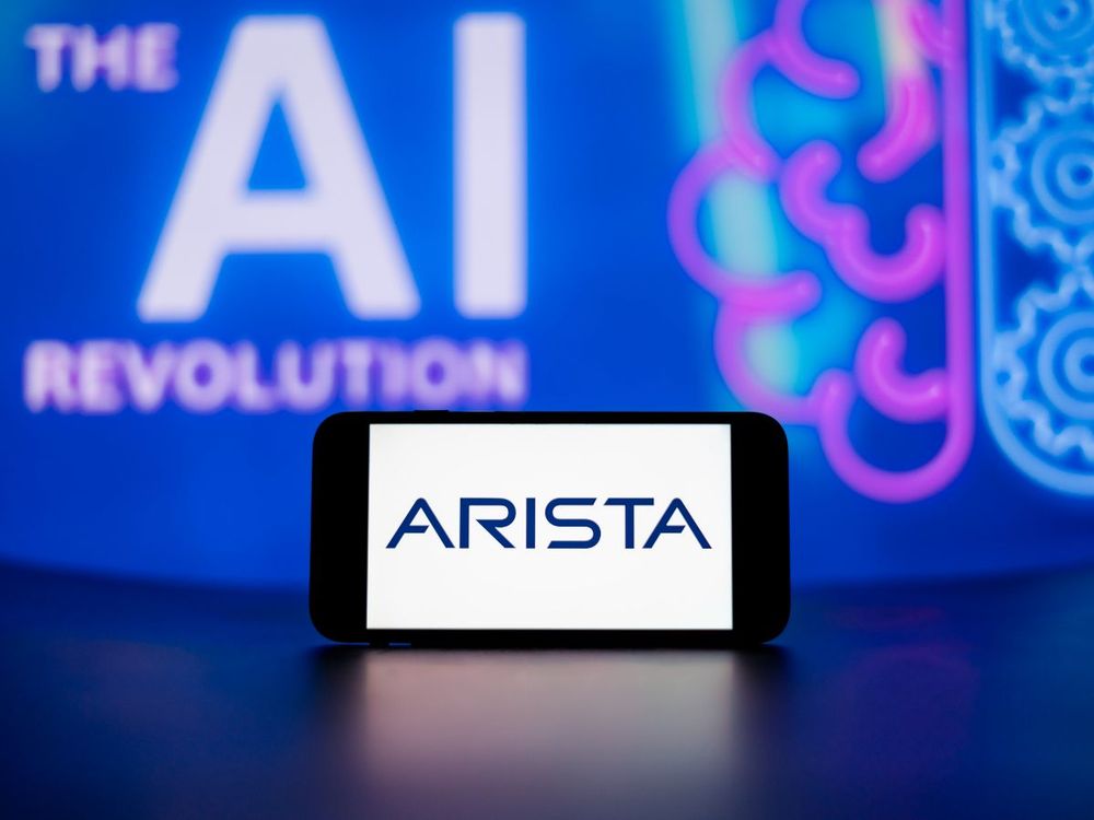  In this photo illustration, the Arista Networks Inc. logo seen displayed on a mobile phone screen with the AI (artificial intelligence) revolution symbol in the background. (Photo Illustration by Idrees Abbas/SOPA Images/LightRocket via Getty Images)