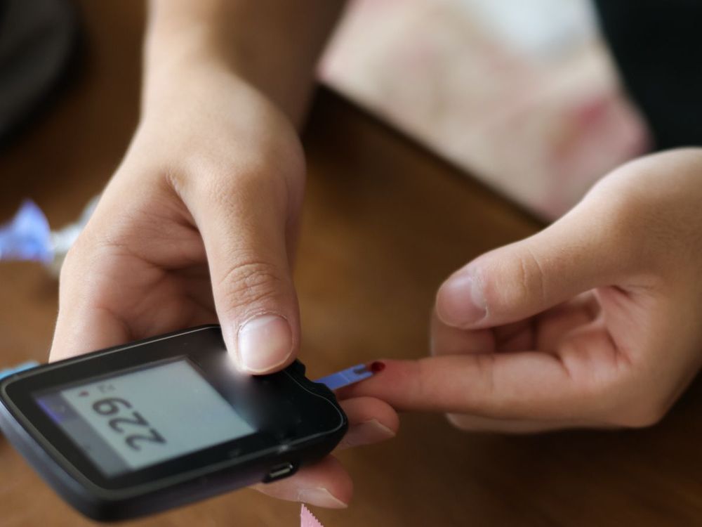 An Asian teenager with type 1 diabetes uses an at home glucometer to test his blood sugar levels. | Image source: Getty Images