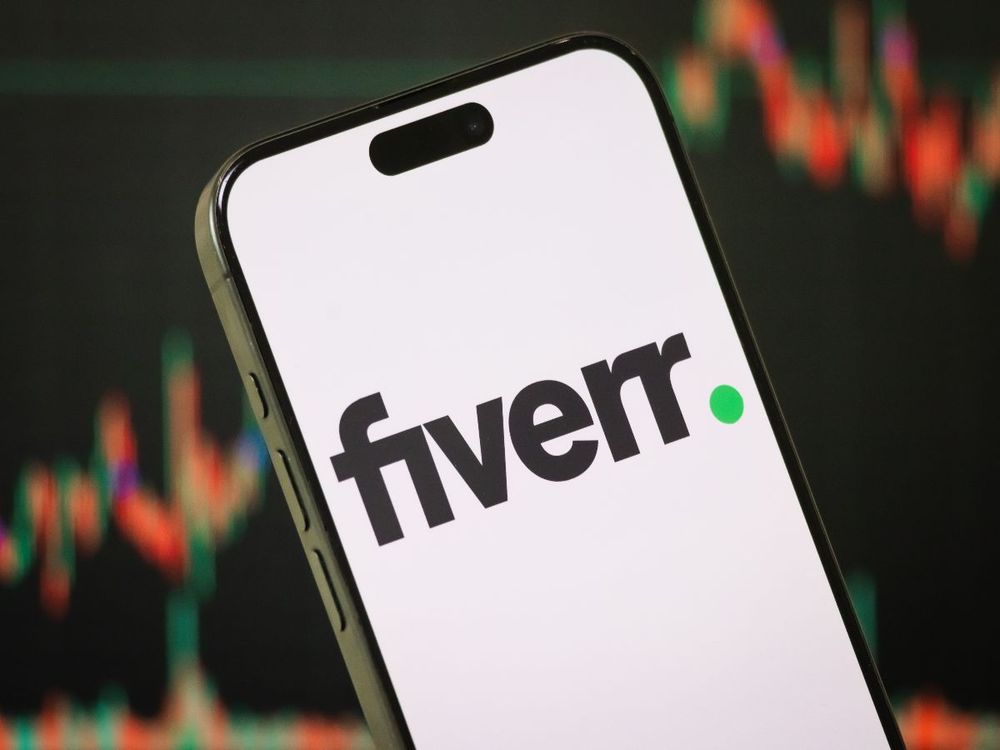 In this photo illustration, the Fiverr logo is displayed on a smartphone screen in front of a stock chart showcasing Fiverr's financial performance on Feb. 16, 2025, in Chongqing, China. (Photo by Cheng Xin/Getty Images)