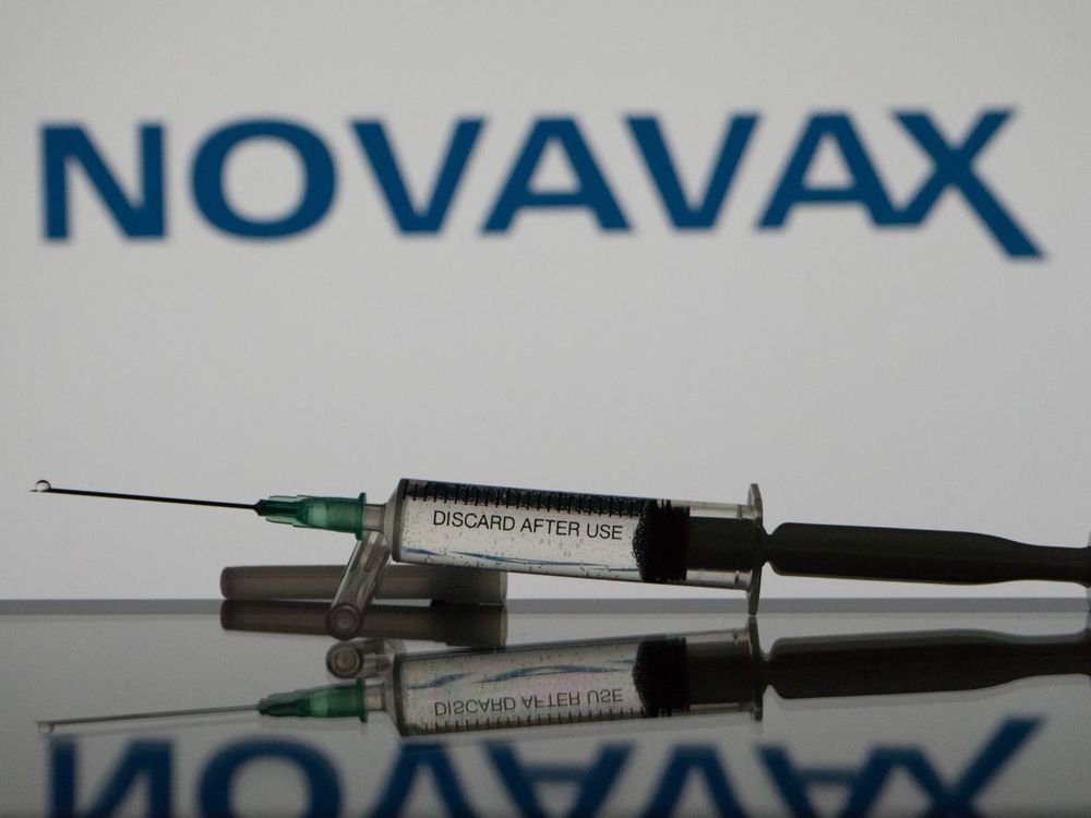 In this photo illustration a covid-19 vaccine is seen with the Novavax logo in the background. (Photo Illustration by Nikos Pekiaridis/NurPhoto via Getty Images)