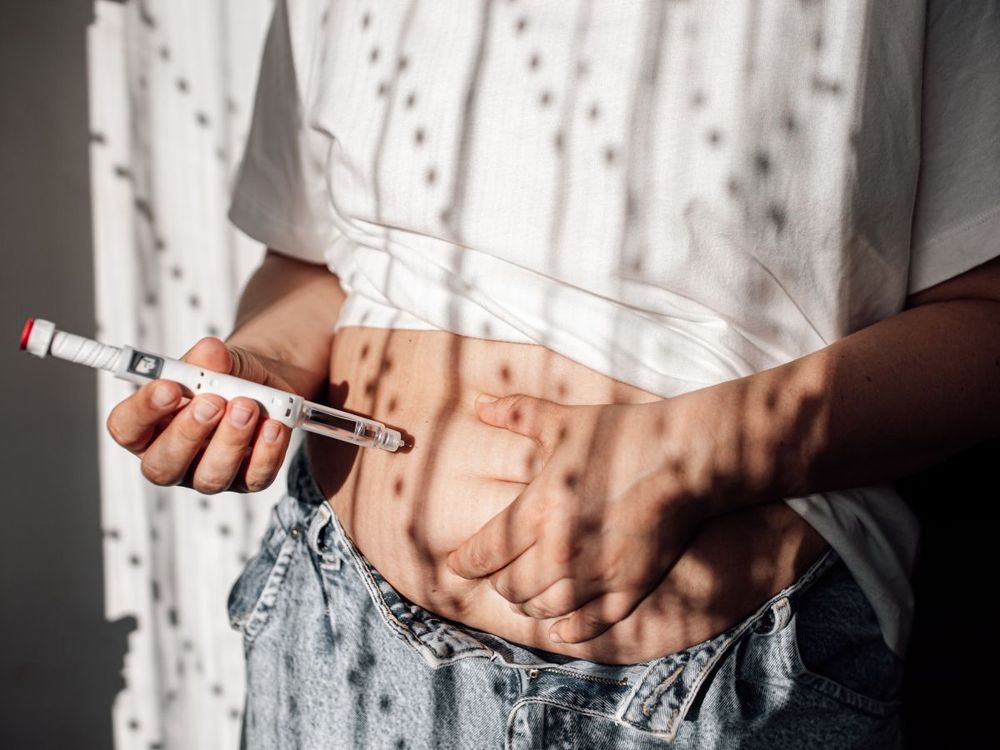 Injections for weight loss with Semaglutide. An obese woman gives a hormone glucagon-like peptide-1 (GLP-1) injection into the abdomen with a pen syringe.