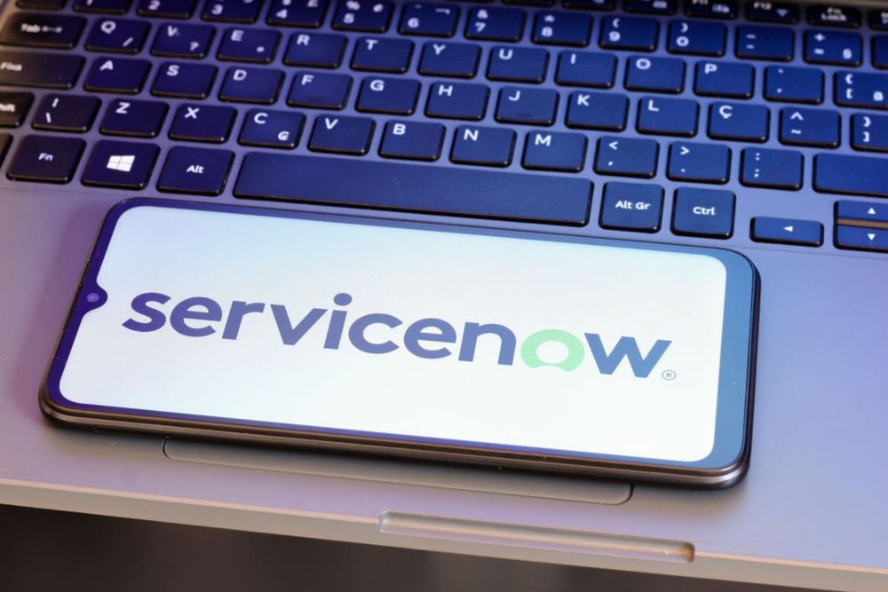  In this photo illustration, the ServiceNow logo is displayed on a smartphone screen next to a laptop keyboard.