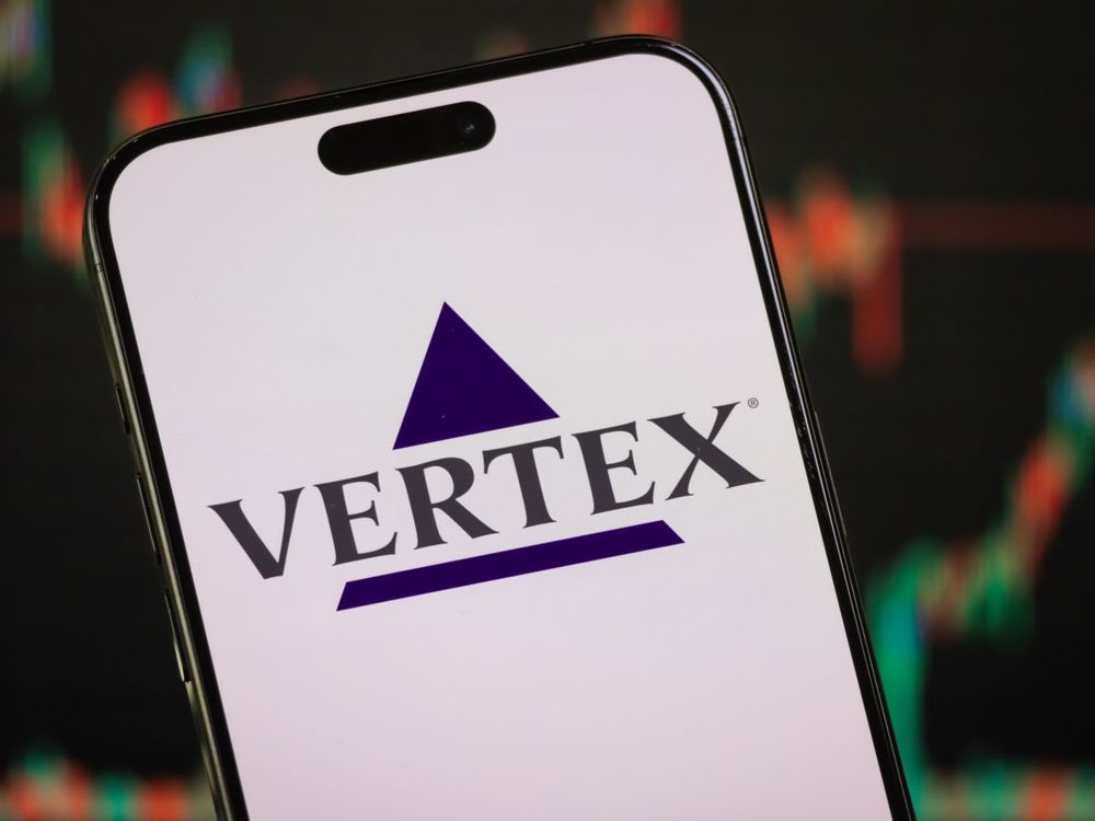 In this photo illustration, Vertex Pharmaceuticals' logo is displayed on a smartphone screen in front of a stock chart. (Photo illustration by Cheng Xin/Getty Images)